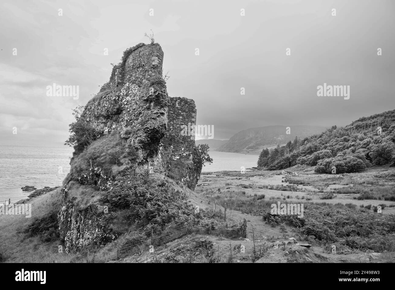 Un'immagine in bianco e nero dei resti di un castello costiero sull'isola di Raasay, in Scozia. Foto Stock