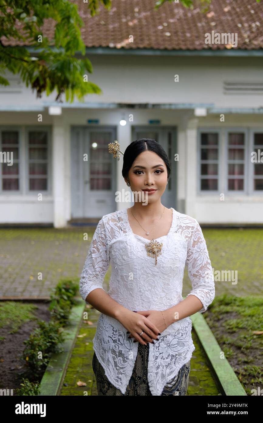 Una giovane donna indonesiana con una felice espressione di successo che indossa un kebaya bianco. Kartini's Day. Foto Stock