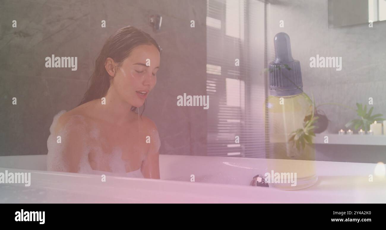 Immagine di una bottiglia contagocce di olio essenziale sopra la donna caucasica in bagno che spruzza la faccia Foto Stock