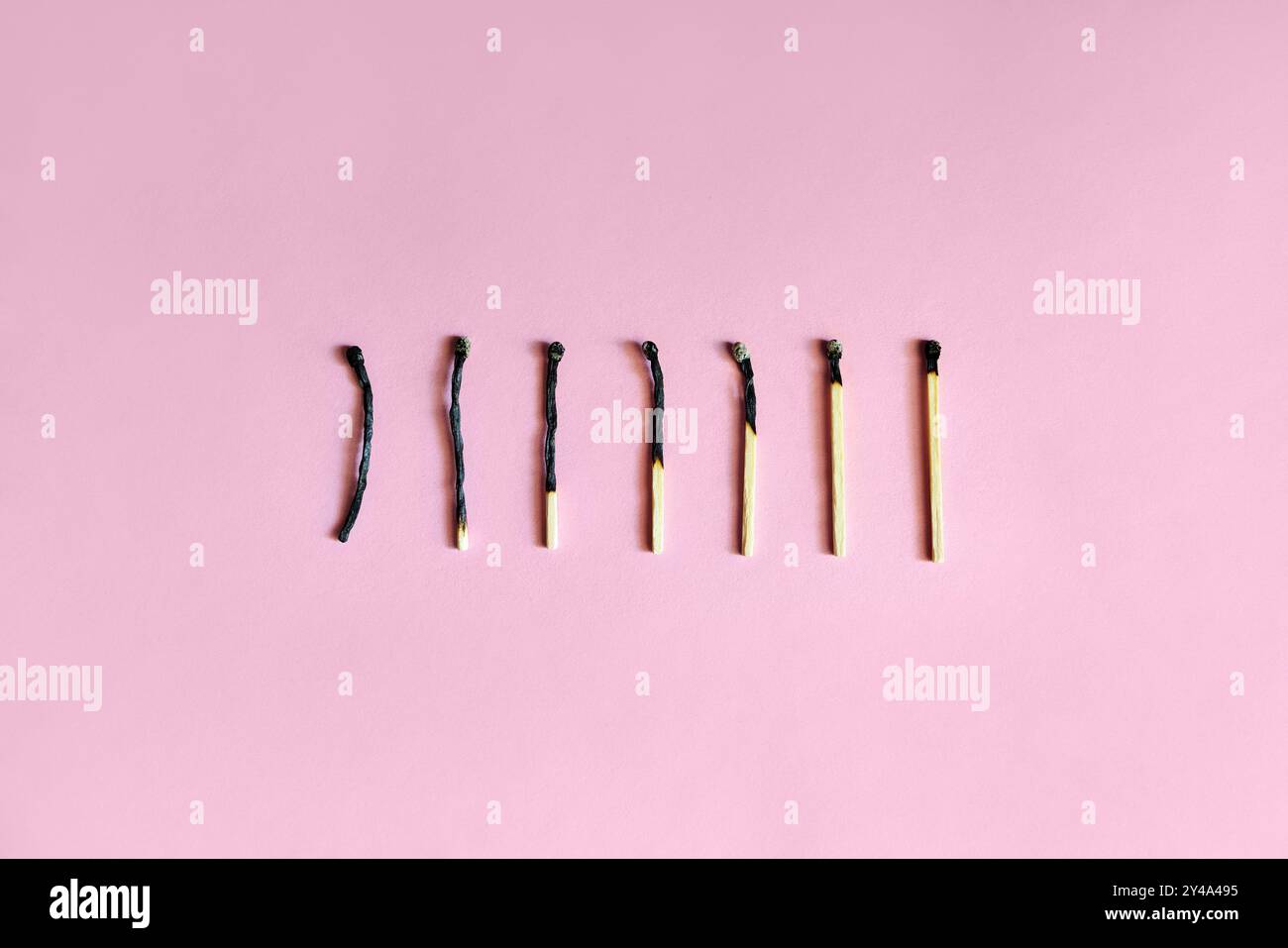 Corrispondenze bruciate su sfondo rosa. Concetto di esaurimento emotivo Foto Stock