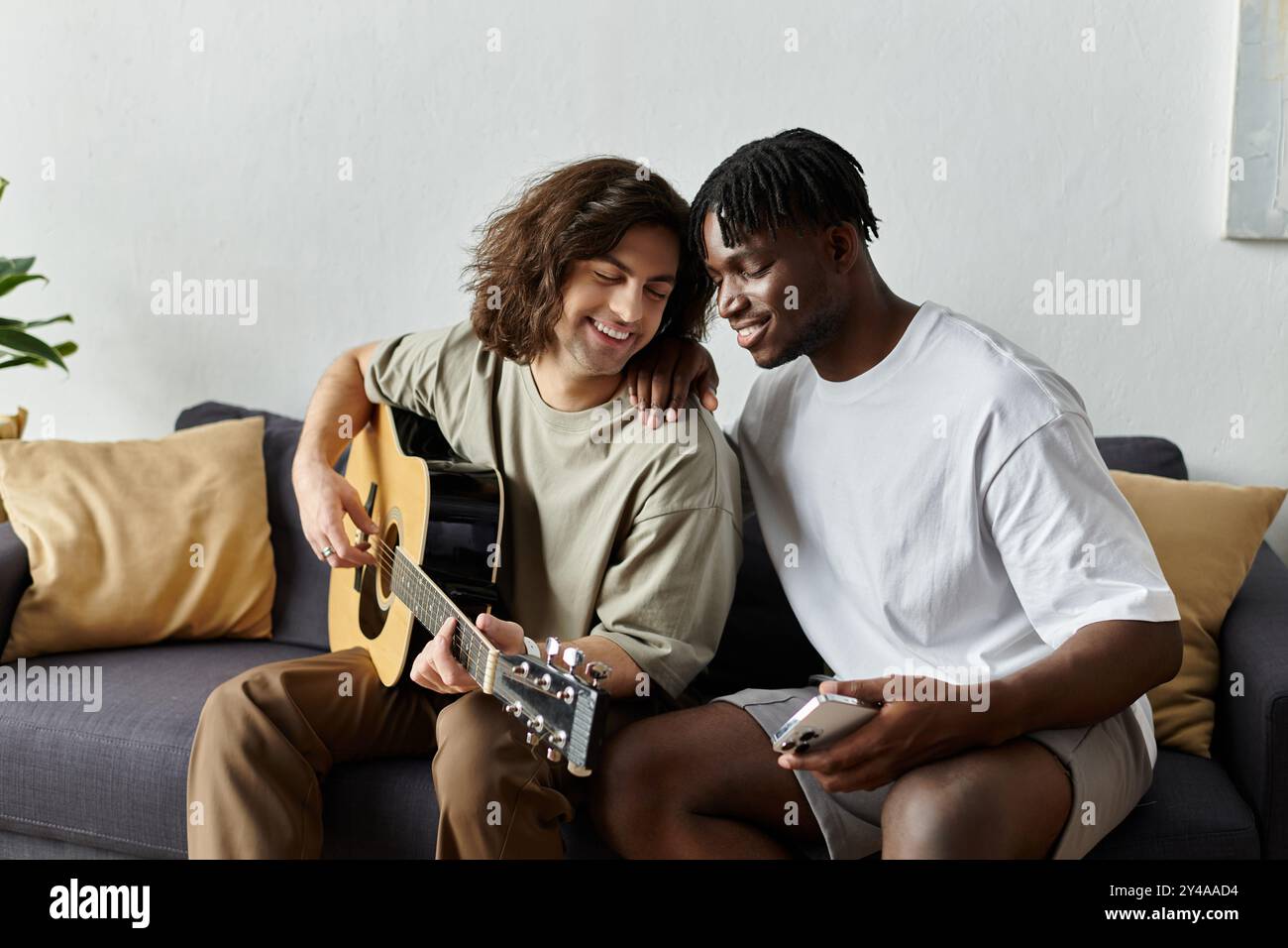 Due partner si godono un momento di gioia a casa, condividendo musica e sorrisi mentre si connettono profondamente. Foto Stock