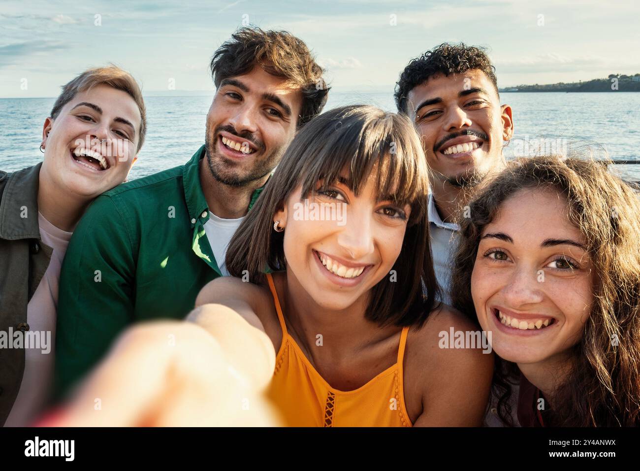 Primo piano di un gruppo multiculturale di giovani adulti che catturano un momento allegro di selfie durante una vacanza in spiaggia. Mostrare amicizia, diversità e generazione Foto Stock