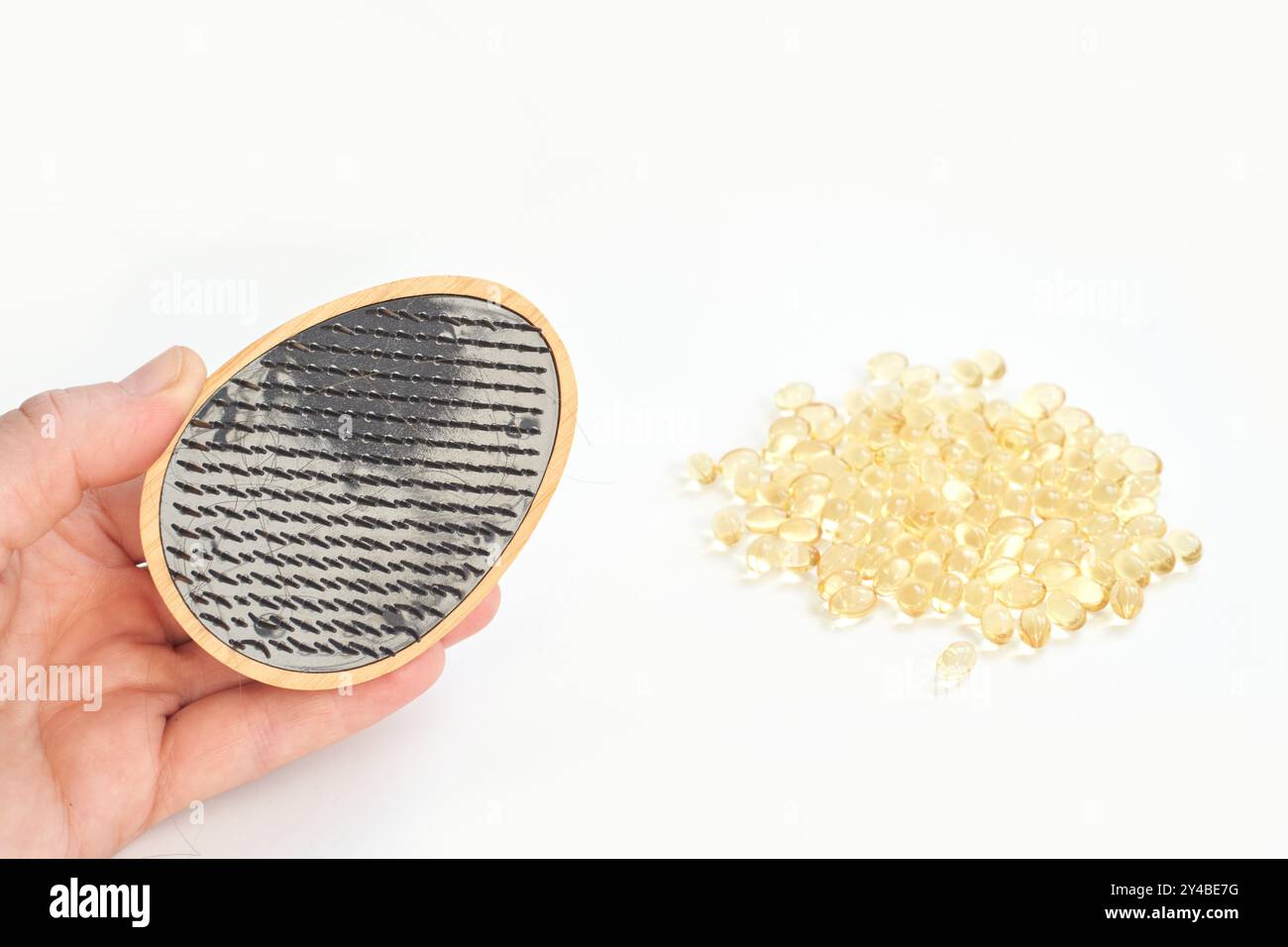 Mano che regge la vista microscopica di microplastiche con capsule su sfondo bianco. Foto Stock