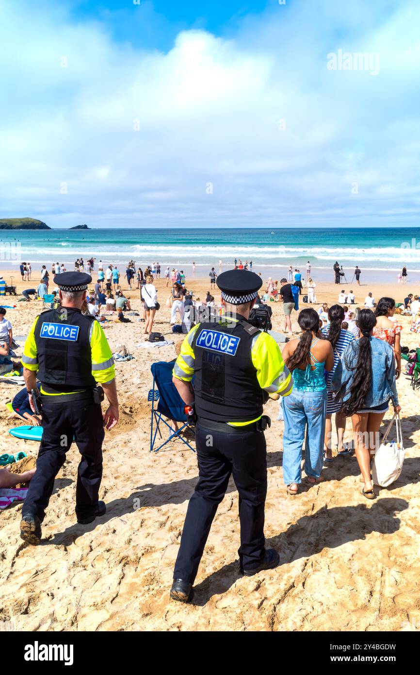 Due agenti della polizia del Devon e della Cornovaglia che pattugliano tra i vacanzieri che si divertono sulla Fistral Beach a Newquay in Cornovaglia nel Th Foto Stock