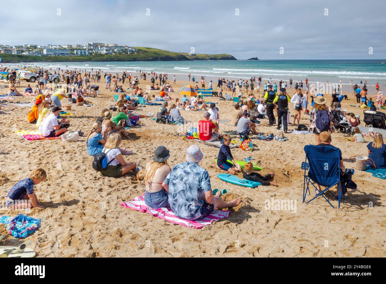 Due agenti maschili della forza di polizia del Devon e della Cornovaglia che pattugliano tra i vacanzieri che si divertono sulla Fistral Beach a Newquay in Cornovaglia Foto Stock