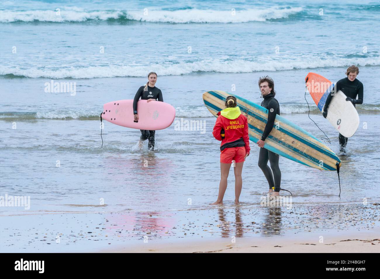 Una bagnina RNLI che fornisce consigli sulla sicurezza ai surfisti sulla spiaggia di Fistral a Newquay in Cornovaglia nel Regno Unito. Foto Stock