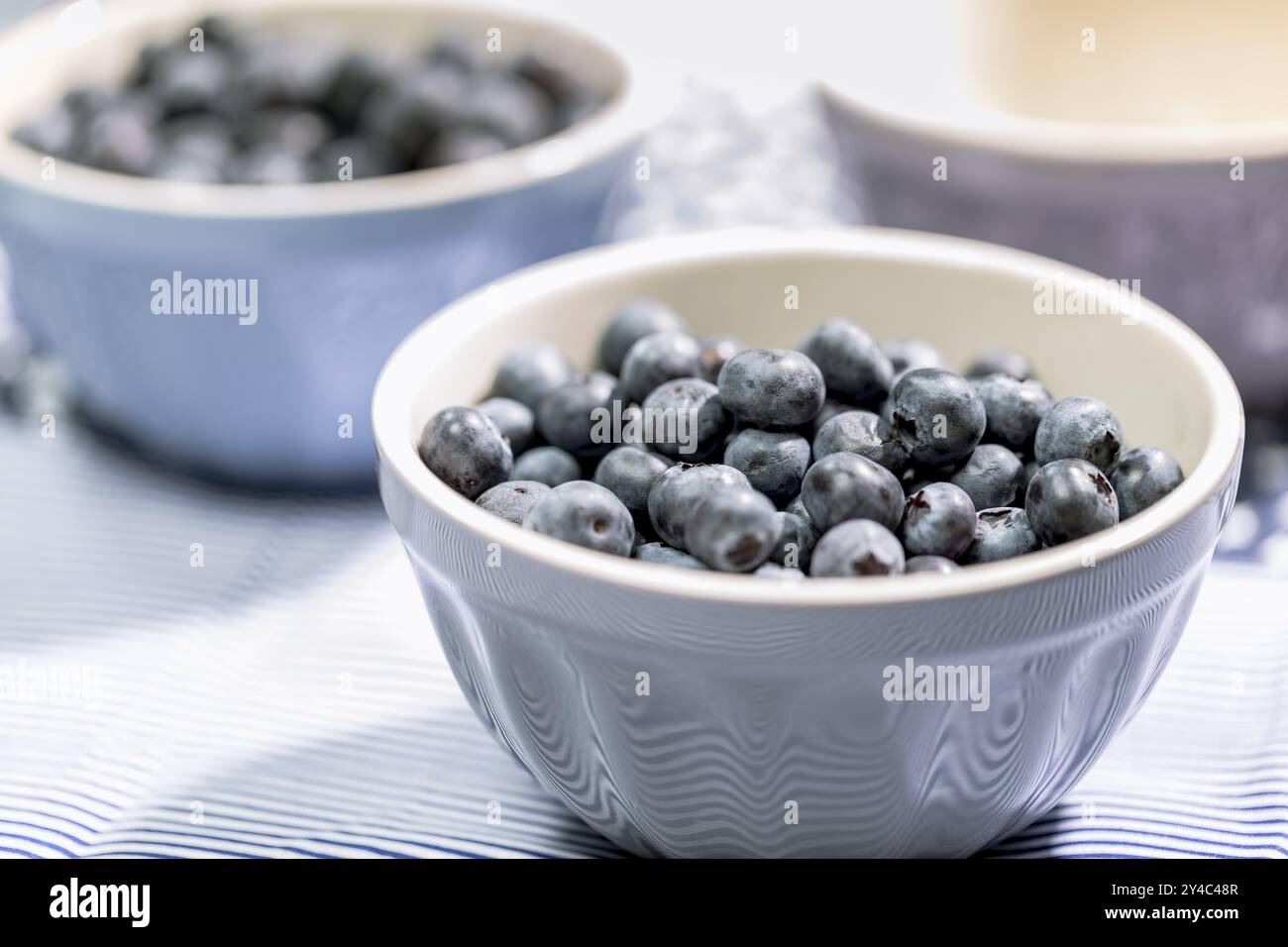 Mirtilli in una piccola ciotola grigia su sfondo azzurro, primo piano Foto Stock