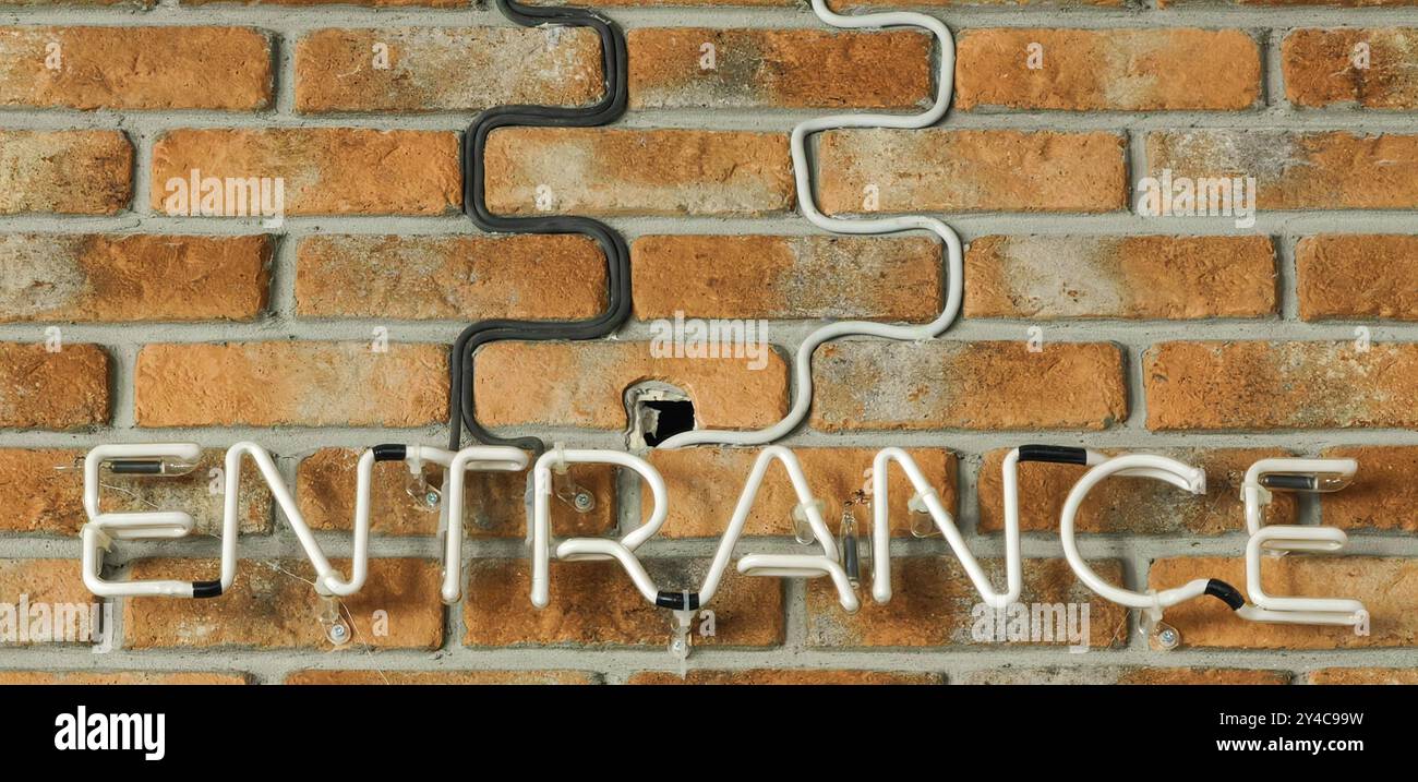Lettere di luce al neon sulla parete in mattoni: Insegna di ingresso illuminata. Foto Stock