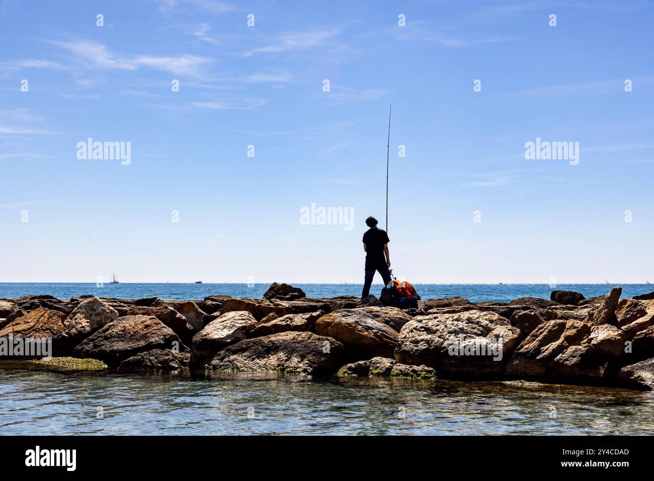 Un uomo pesca al largo della costa di Alicante, in Spagna. Foto Stock