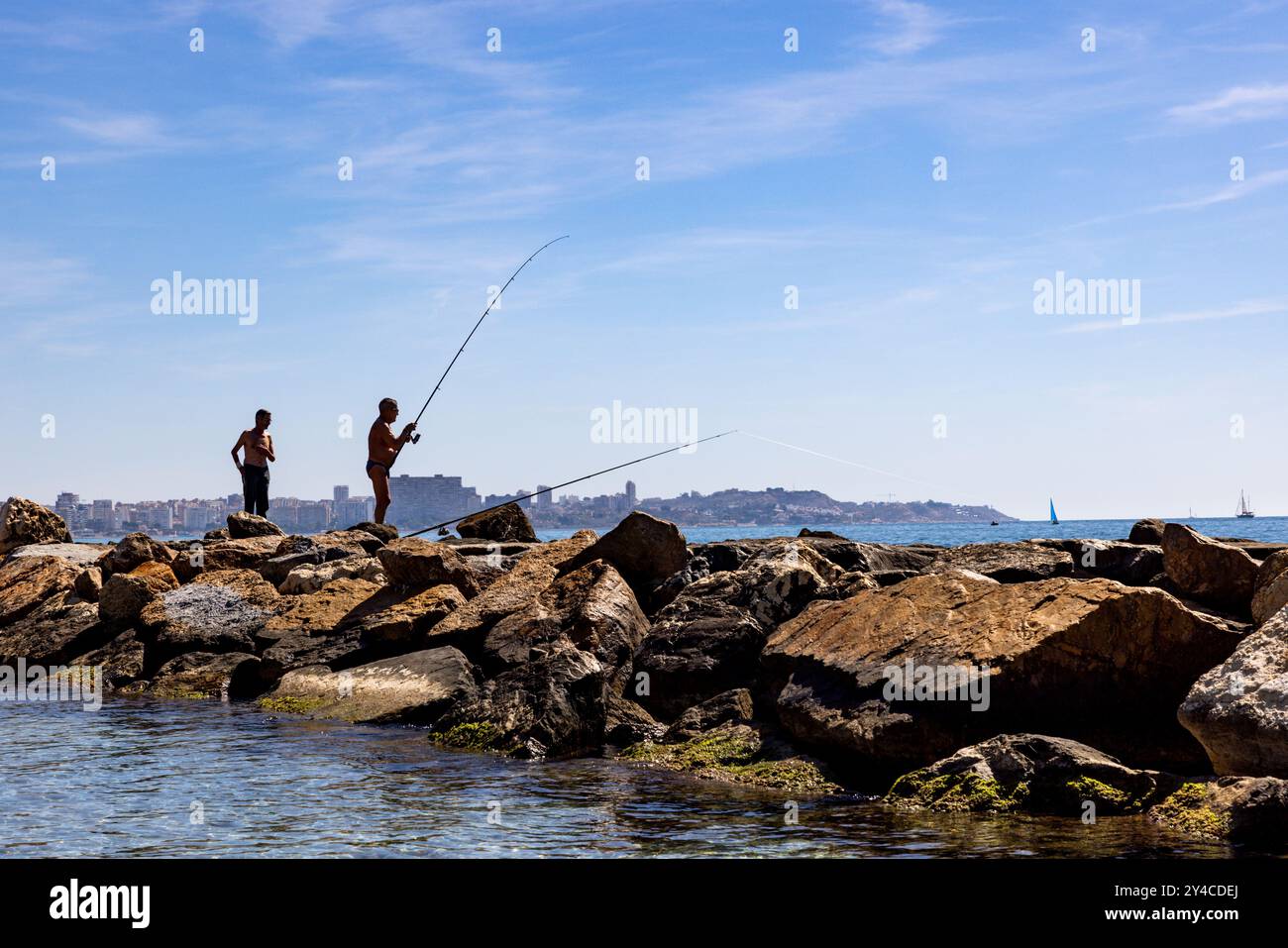 Un uomo pesca al largo della costa di Alicante, in Spagna. Foto Stock