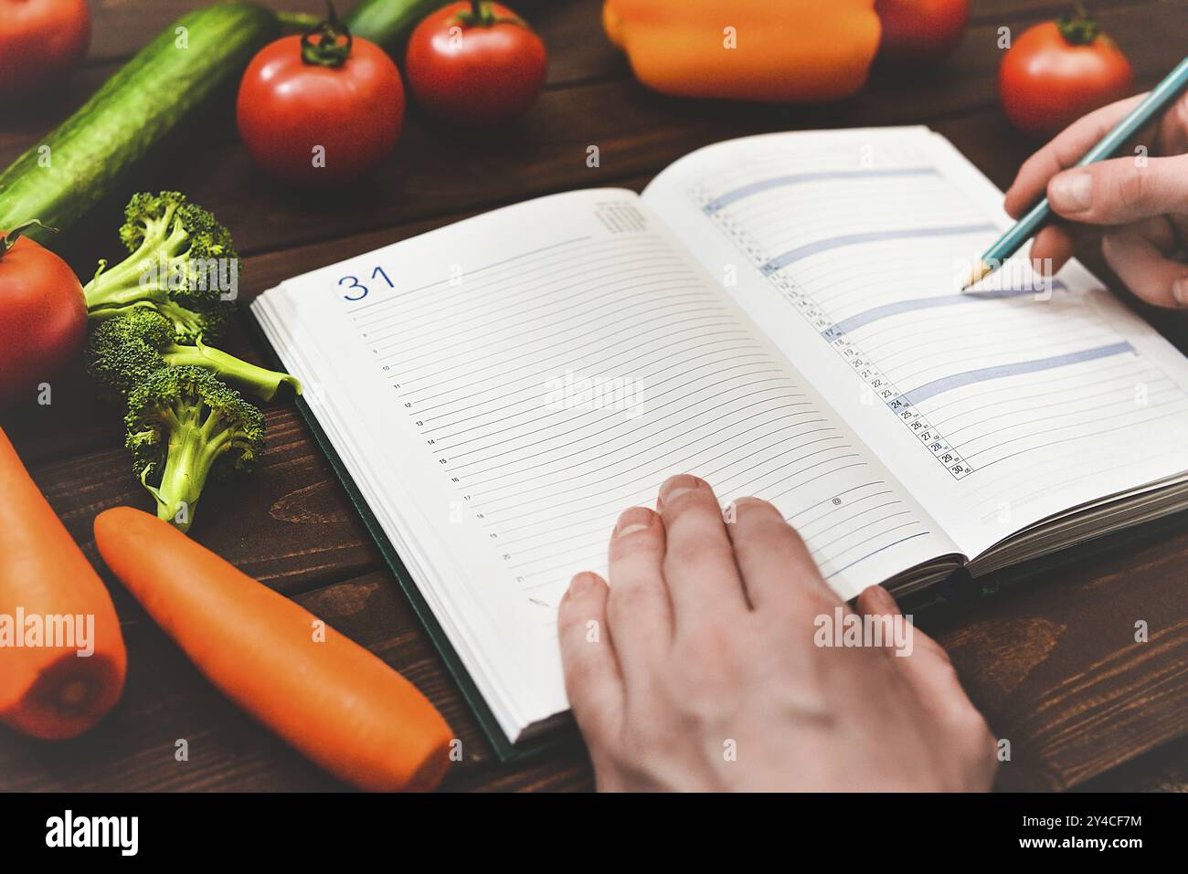 Concetto di dieta con blocco note e penna circondati da un sacco di verdure fresche e salutari Foto Stock