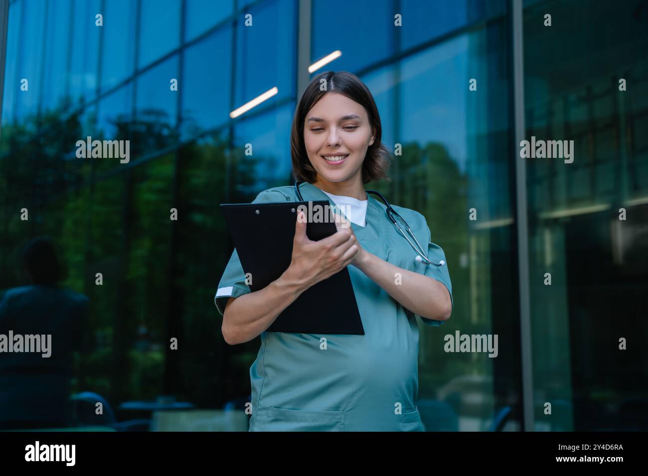 Gravidanza sorridente giovane medico con un elenco di prescrizioni in mano Foto Stock