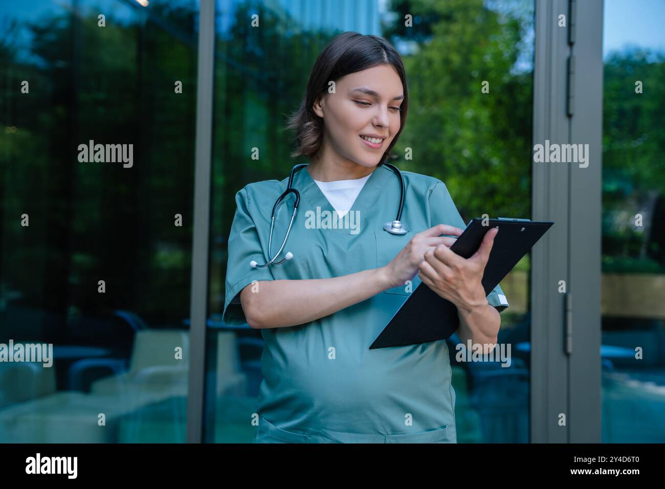 Gravidanza sorridente giovane medico con un elenco di prescrizioni in mano Foto Stock