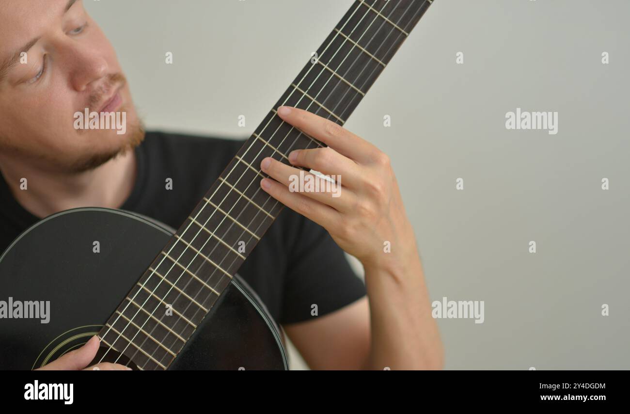 Un uomo che suona la chitarra. Mani sulle corde. Primo piano verticale. Selezione corda. Musicista che suona la chitarra elettrica. Sfondo per striscioni con spazio di copia Foto Stock
