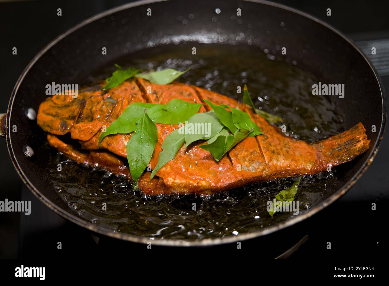 Questo pesce vivace, fritto alla perfezione con spezie aromatiche e foglie di curry fresche, stuzzica l'appetito e aggiunge sapore a qualsiasi progetto Foto Stock
