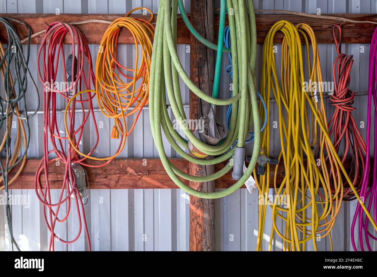 Cavi di prolunga elettrici colorati appesi alla parete interna di un fienile Foto Stock