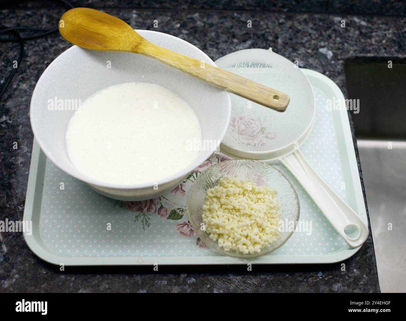 Un'immagine che mostra il processo di preparazione del kefir fatto in casa con chicchi tesi e cremoso kefir in una ciotola Foto Stock