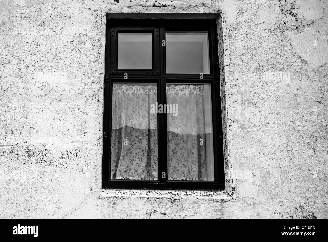 finestra in bianco e nero con vecchie tende in pizzo su pareti bianche Foto Stock