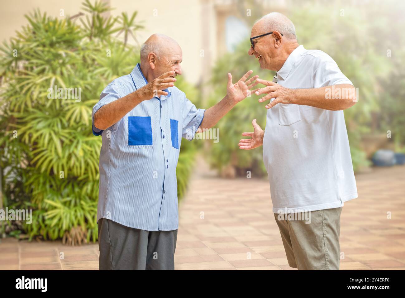 Due amici anziani si incontrano e sono felici di vederci all'aperto Foto Stock