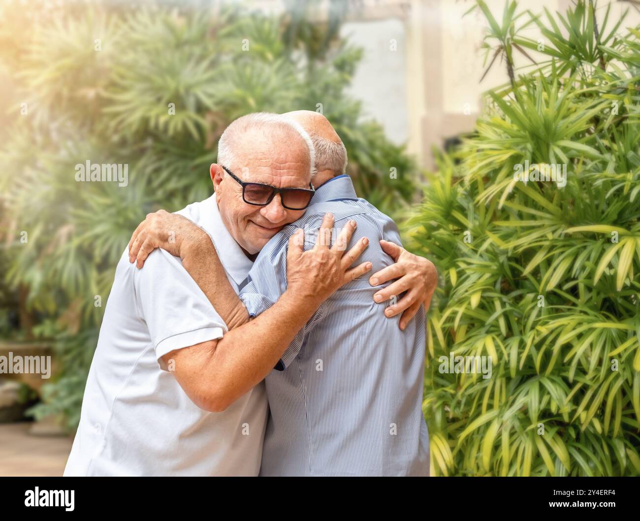 Due amici anziani si abbracciano quando si incontrano all'aperto Foto Stock