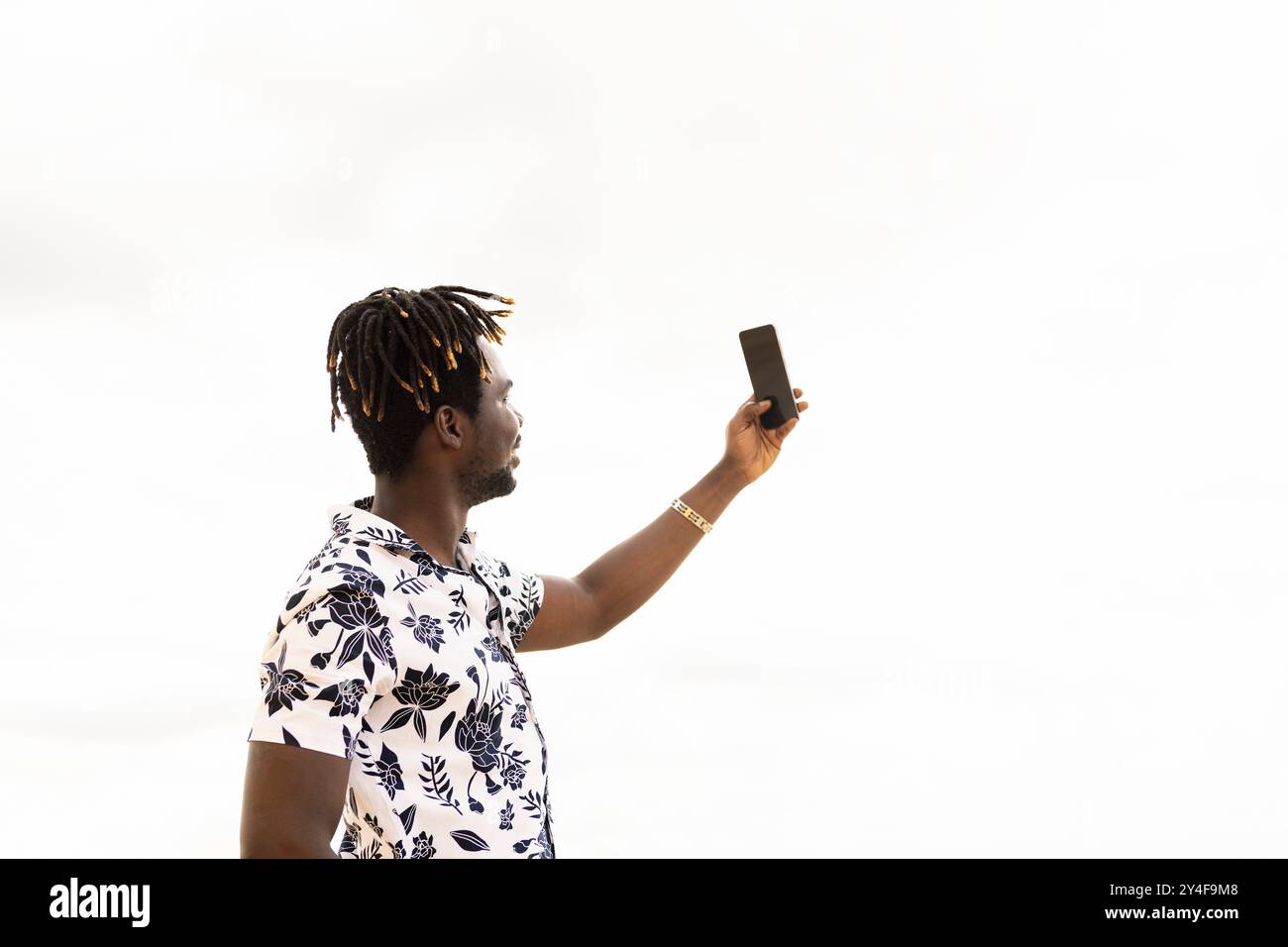 giovane uomo nero elegante che scatta una foto con il telefono Foto Stock