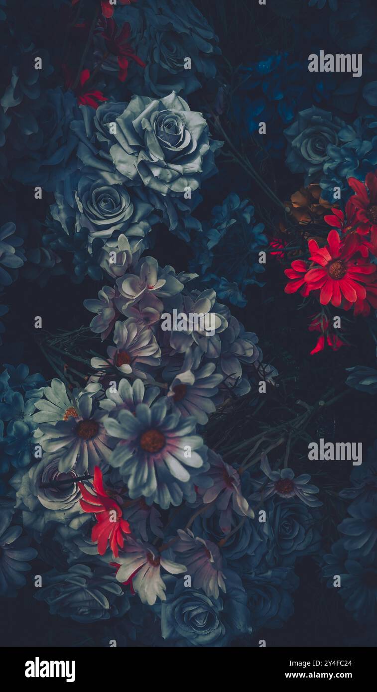 Un bouquet di fiori artificiali, principalmente rose blu, con accenti di rosso e bianco, in un'estetica vintage. Foto Stock