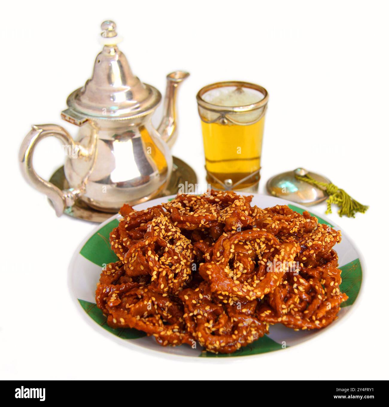 Cibo marocchino. Biscotti Chebakia dolci ricoperti di miele con semi di sesamo e tè alla menta. Tipicamente consumato alla fine del Ramadan. Isolato su bianco Foto Stock