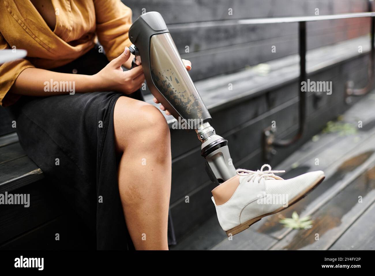 In un accogliente caffè, una giovane donna con un arto artificiale si rilassa sulla panchina, abbracciando il suo stile di vita unico. Foto Stock