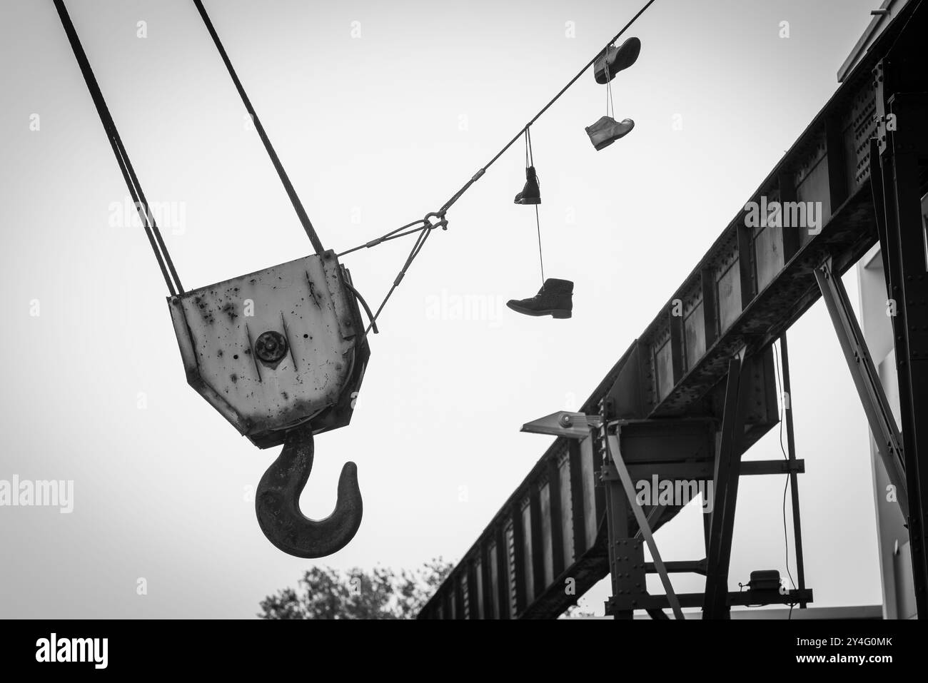 Foto dettagliata di un grande gancio per gru, evidenziato da un paio di vecchie scarpe appese accanto al gancio della gru, foto fineart Foto Stock