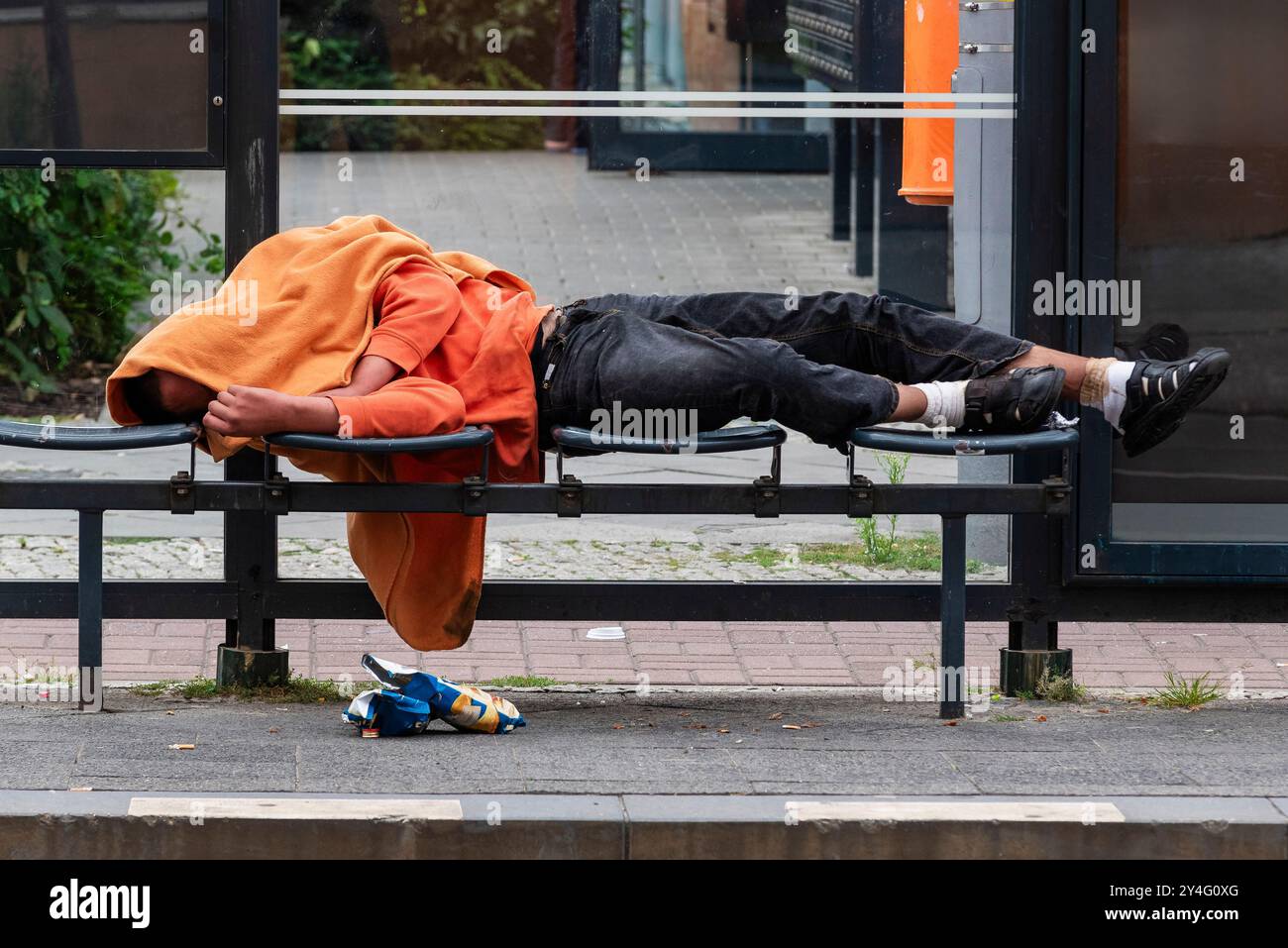 Homless Man che dorme in una stazione del tram, Una persona ubriaca giace in una fermata del tram e dorme sulla sua intossicazione Foto Stock