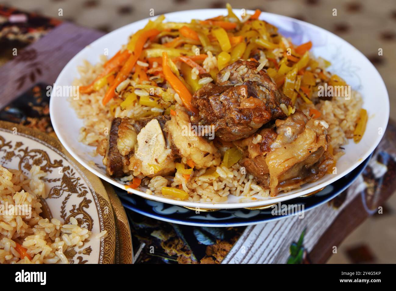 Cucina tradizionale uzbeka orientale, pilaf o plov con grandi pezzi di carne e carote, cucinati in una padella di ghisa nera di kazan'. Messa a fuoco selettiva Foto Stock