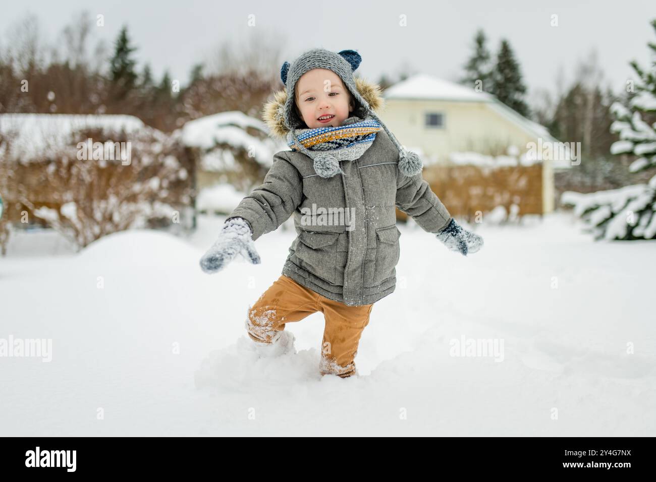 Adorabile bambino che si diverte in una giornata invernale innevata. Un bambino carino che indossa abiti caldi e gioca sulla neve. Attività invernali per famiglie con bambini. Foto Stock