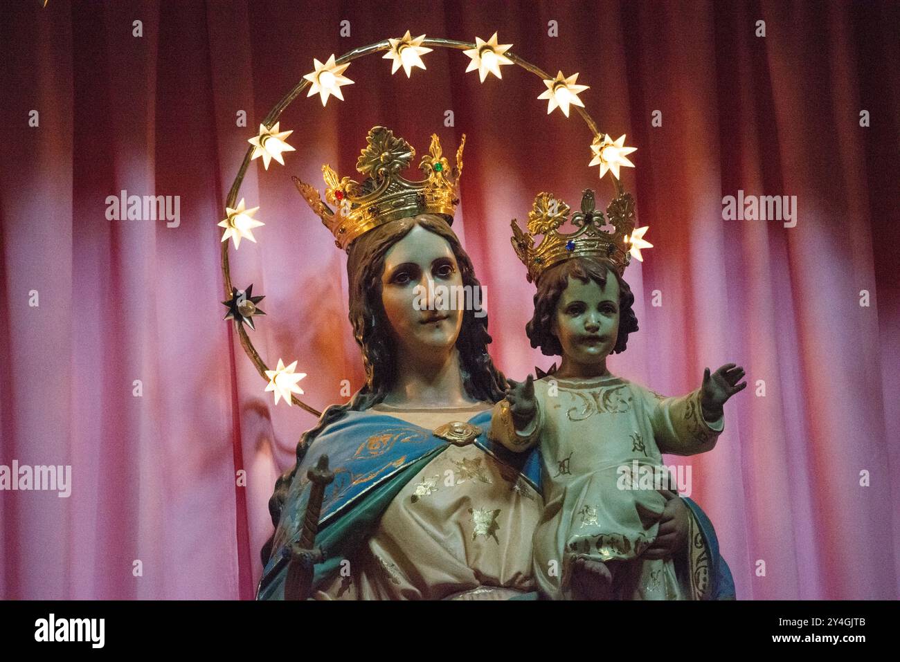 Iglesia de Santa Inés Statua della Madonna e del Bambino Città del Messico | CITTÀ DEL MESSICO, Messico — Una statua della Madonna e del Bambino circondata da luci decorative funge da punto centrale dell’altare maggiore dell’Iglesia de Santa Inés (Chiesa di Sant’Agnese) nel quartiere Centro Histórico. La chiesa, originariamente fondata nel 1600 come parte del Convento de Santa Inés, fu completamente ricostruita tra il 1783-1790 dall’architetto coloniale di fama Francisco Guerrero y Torres. La chiesa rappresentava un esperimento sociale unico in quanto unico convento del Messico ad accettare suore senza requisiti di dote, servendo le donne spagnole povere Foto Stock