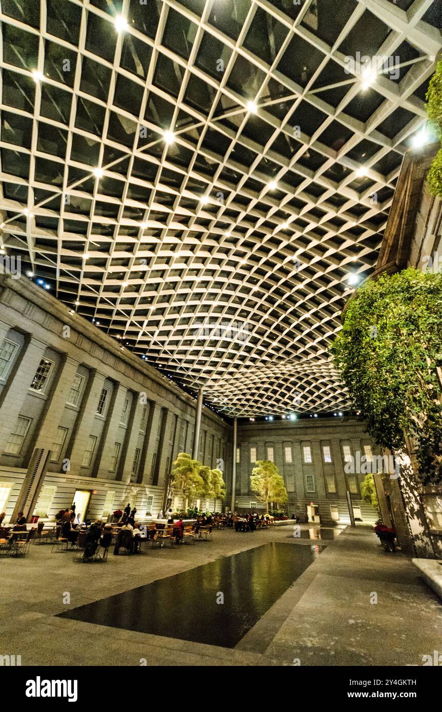 WASHINGTON DC - il Robert and Arlene Kogod Courtyard dello Smithsonian's Donald W. Reynolds Center for American Art and Portraiture, illuminato di notte con il cielo scuro visibile attraverso il suo caratteristico soffitto di vetro. Progettato da Foster + Partners e completato nel 2007, questo 28 cortile coperto di 000 metri quadrati collega lo Smithsonian American Art Museum e la National Portrait Gallery. L'elegante spazio interno presenta una tettoia di vetro ondulata e funge da popolare area di ritrovo pubblico nel centro di Washington, DC. Foto Stock