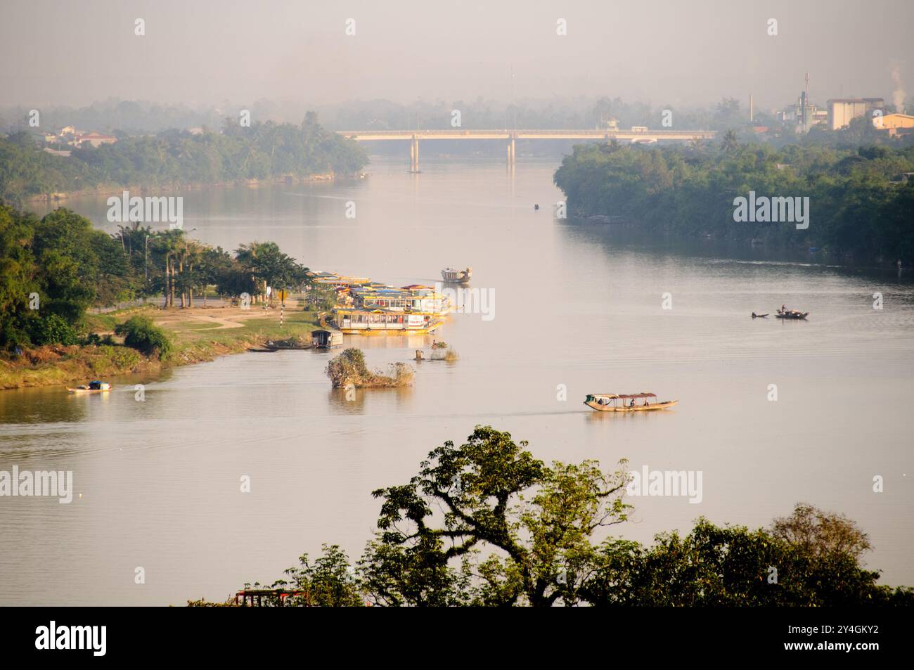 Perfume River Boats Hue Vietnam // HUE, Vietnam - le barche navigano nello storico fiume Perfume (Song Huong), che scorre attraverso il cuore di Hue. Il fiume, che prende il nome dai fiori profumati che una volta caddero dai frutteti lungo le sue rive, continua a servire sia come un percorso di trasporto vitale che come popolare attrazione turistica nell'ex capitale imperiale del Vietnam. Foto Stock