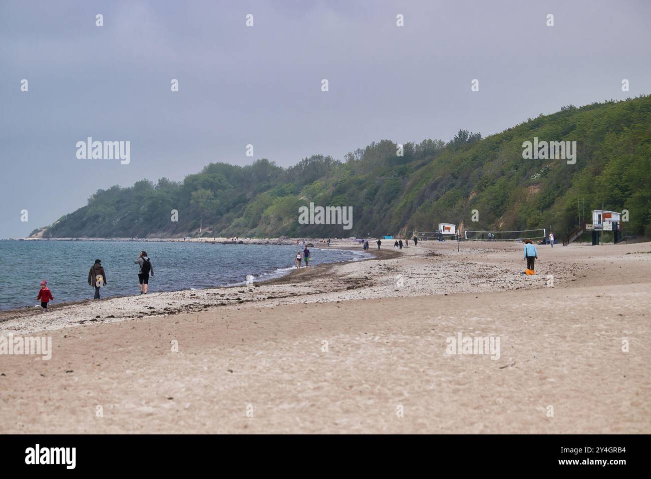 Rerik, Germania - 30 maggio 2021: Persone che camminano su una spiaggia sabbiosa con reti da pallavolo in una nebbiosa giornata primaverile nel Mar Baltico. Foto Stock