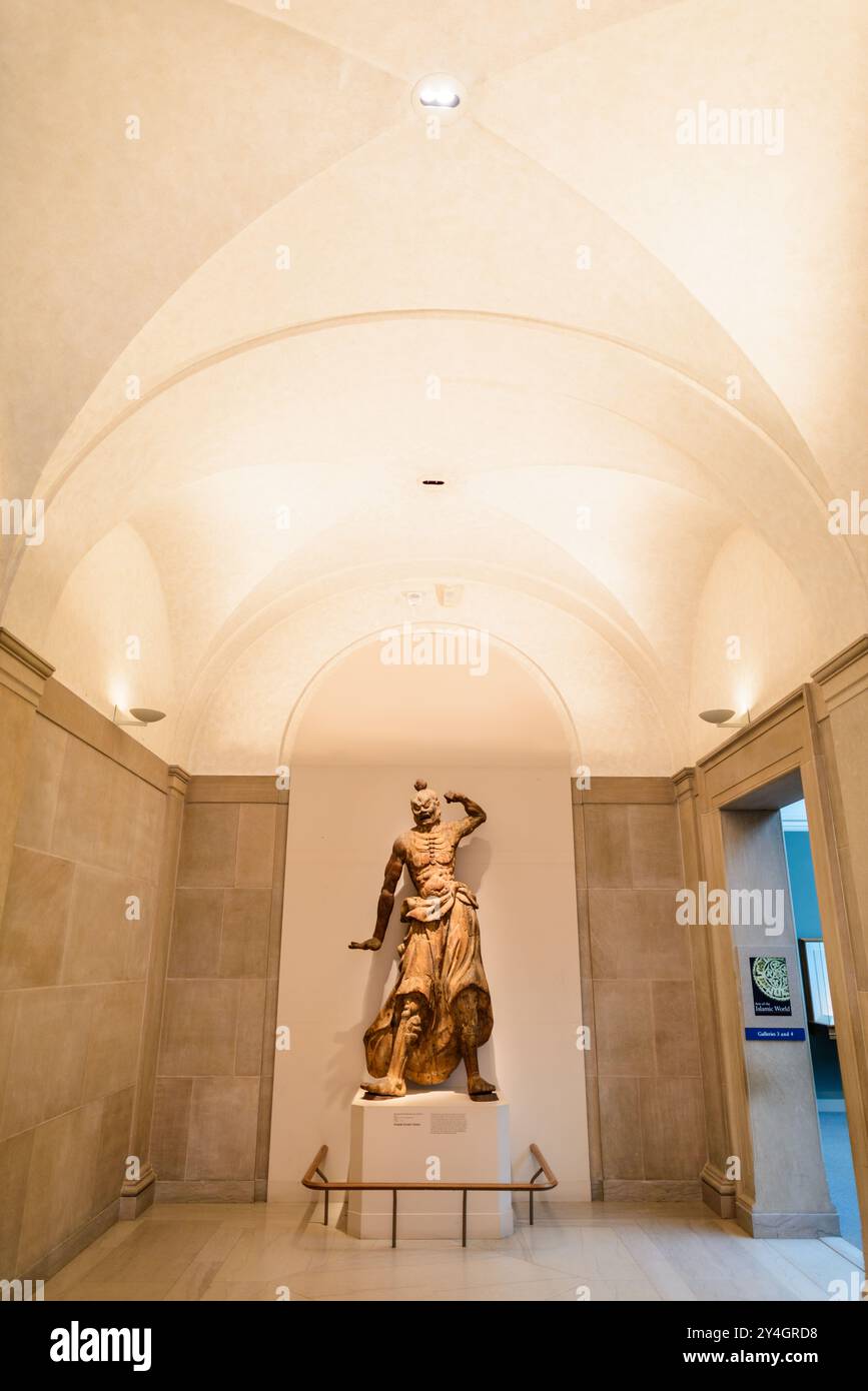 WASHINGTON DC - Una statua di guerriero in legno in mostra in un corridoio della Freer Gallery of Art sul National Mall. Questa imponente scultura, parte della collezione d'arte asiatica dello Smithsonian Institution, mostra l'artigianato e il significato culturale delle figure guerriere nelle tradizioni artistiche asiatiche, sullo sfondo dell'elegante architettura interna della galleria. Foto Stock