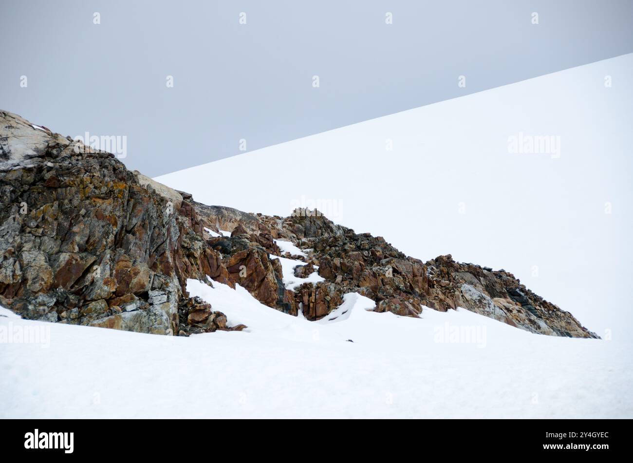 Paesaggio dell'isola di Petermann Penisola Antartica // ISOLA DI PETERMANN, Antartide - Una vista del paesaggio sull'isola di Petermann, situata al largo della costa occidentale della Penisola Antartica. Il terreno accidentato dell'isola è caratterizzato da un mix di affioramenti rocciosi, aree innevate e acque circostanti punteggiate da banchi di ghiaccio. Petermann Island è conosciuta per le sue colonie di Adelie e pinguini gentoo e serve come destinazione popolare per le spedizioni antartiche. Foto Stock