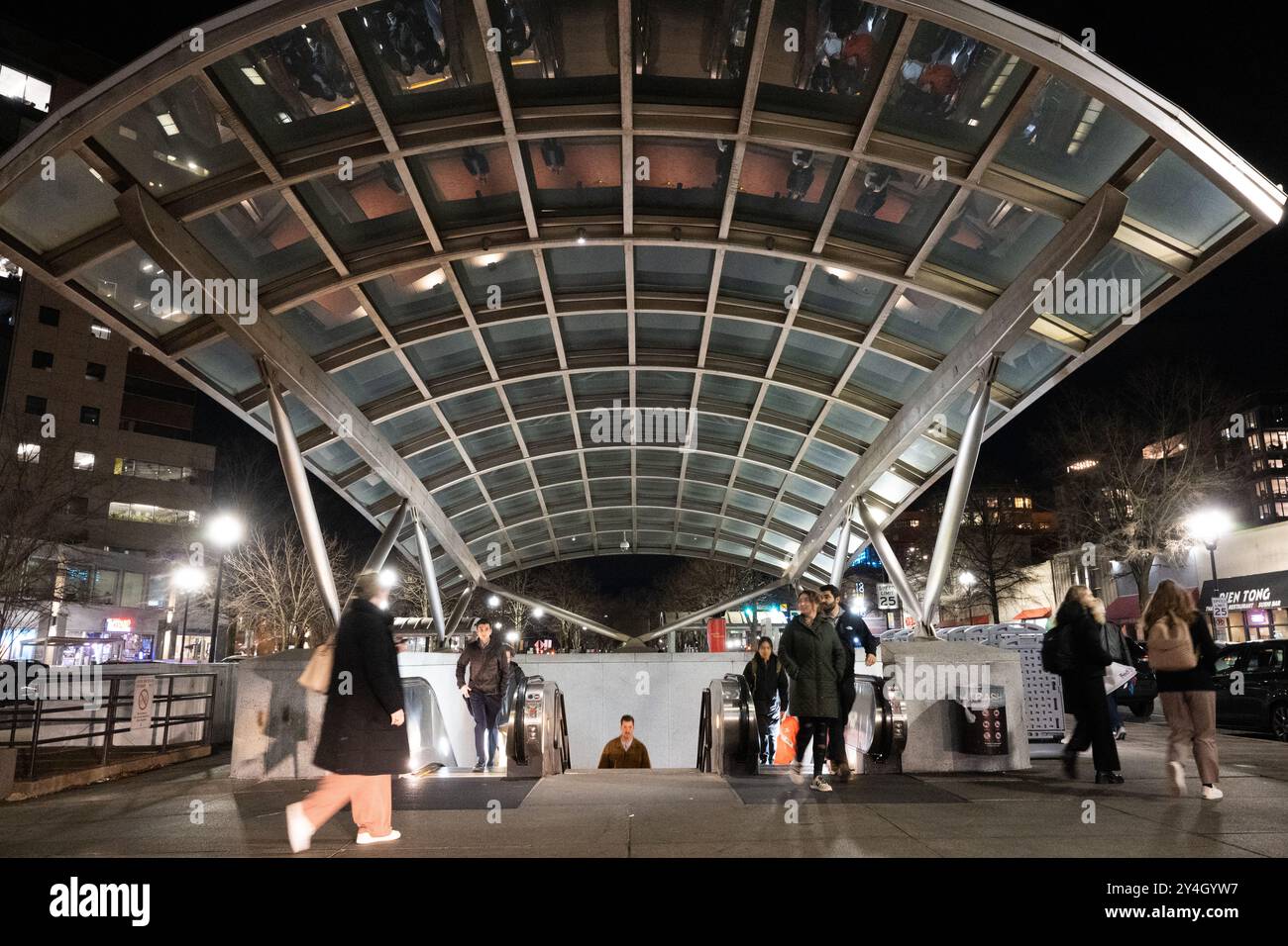ARLINGTON, Virginia - l'ingresso illuminato della stazione della metropolitana di Clarendon mostra l'architettura distintiva del sistema della metropolitana di Washington di notte. Situata nel cuore del quartiere di Clarendon, questa stazione della linea Orange funge da importante nodo di transito. Il design moderno e l'illuminazione dell'ingresso creano una presenza suggestiva nel paesaggio urbano. Foto Stock