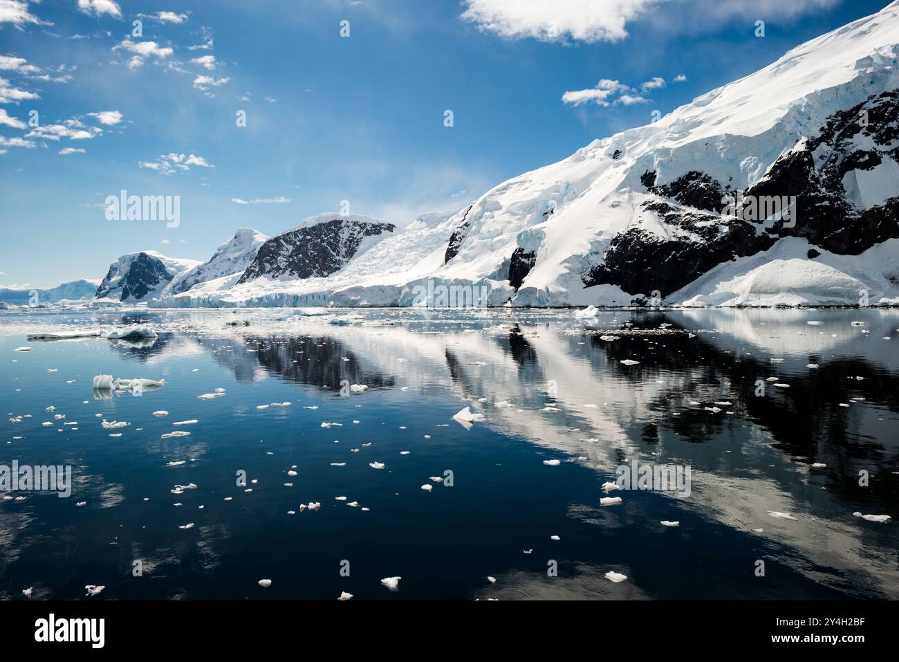 NEKO HARBOR, Antartide: Le montagne panoramiche ghiacciate e rocciose ricoperte di ghiaccio e neve a Neko Harbour, sulla penisola antartica, si riflettono su acque calme simili a specchi. Foto Stock