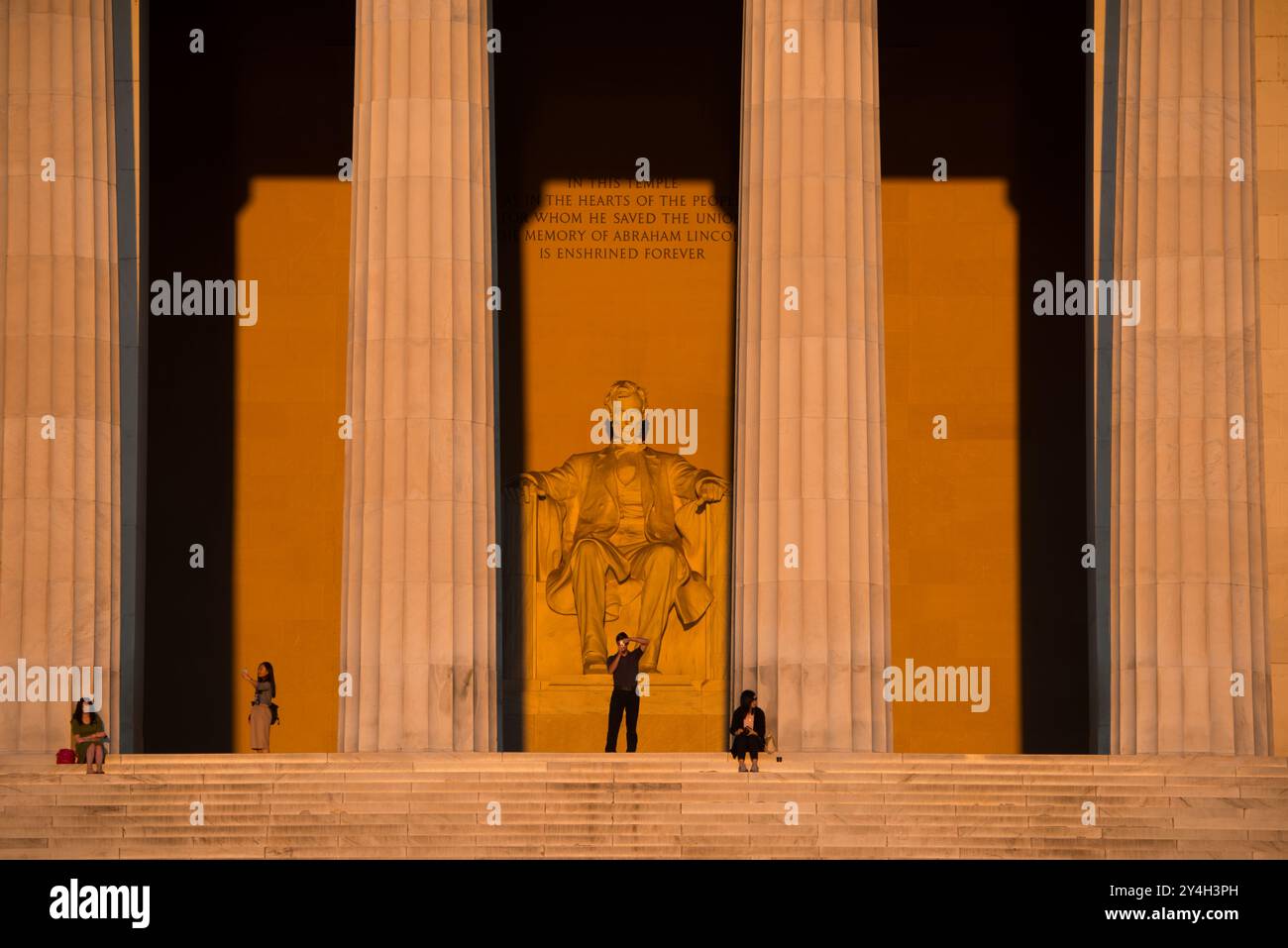 WASHINGTON DC, Stati Uniti: La statua di Abraham Lincoln all'interno del Lincoln Memorial è illuminata dalla luce naturale dorata del sole subito dopo l'alba. Questo effetto luminoso, visibile intorno all'equinozio primaverile e autunnale, esalta la grandezza del monumento mentre il sole splende attraverso l'ingresso orientale. Il Lincoln Memorial, situato sul National Mall, è uno dei monumenti più iconici degli Stati Uniti. NB: Il colore e l'illuminazione sono naturali. Foto Stock