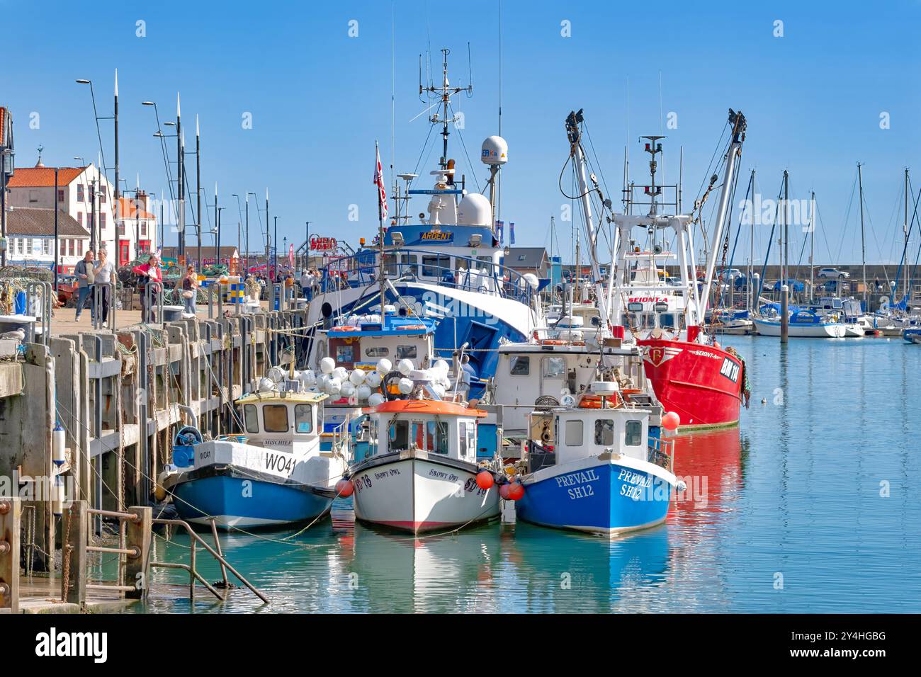 Scarborough, Yorkshire. Una vista del Porto di Scarborough con piccole e grandi barche da pesca dai colori vivaci ormeggiate contro le mura del porto Foto Stock