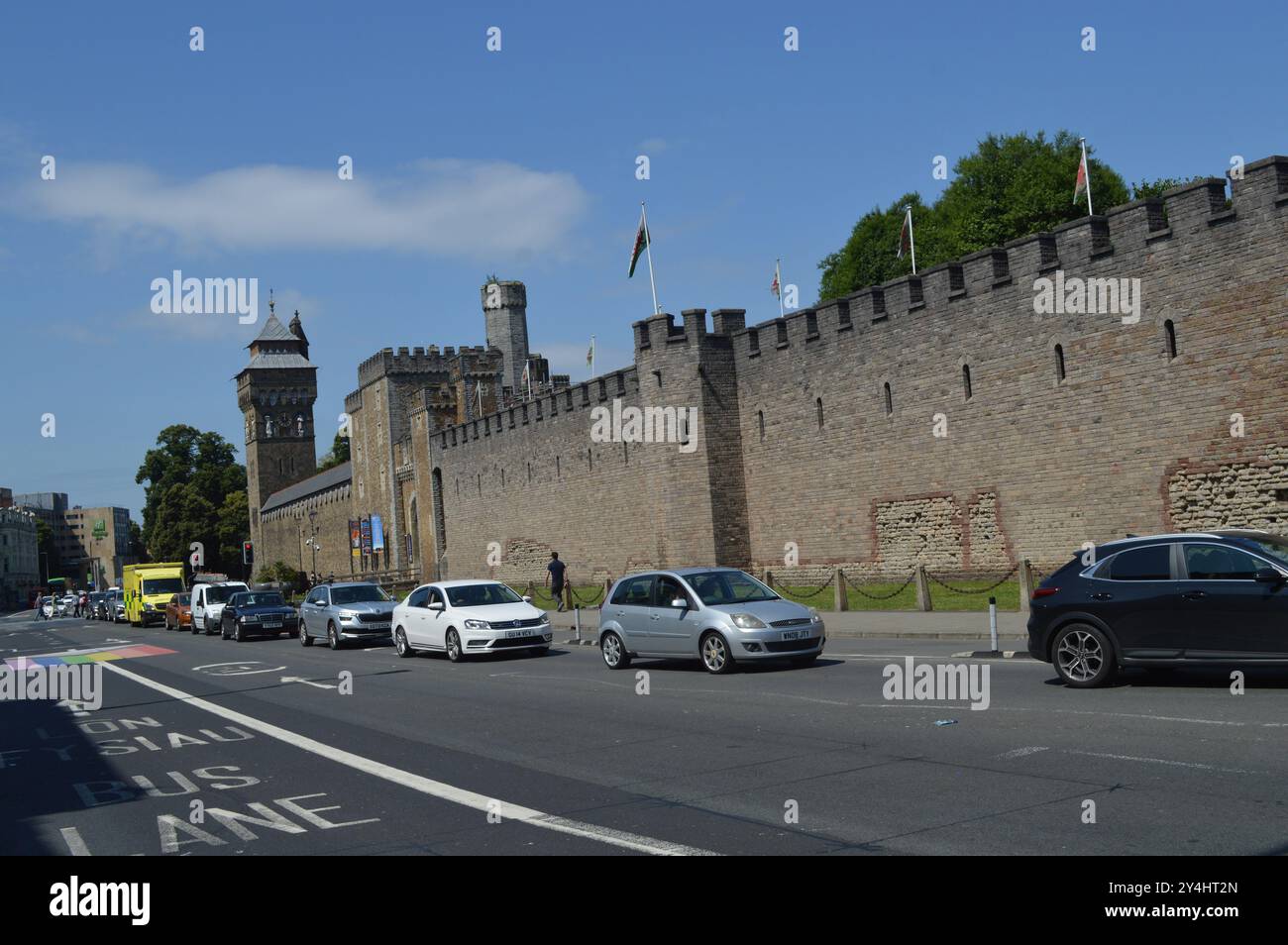 I veicoli oltrepassano la Torre dell'Orologio e le mura del Castello di Cardiff. Cardiff, Galles, Regno Unito. 18 luglio 2024. Foto Stock