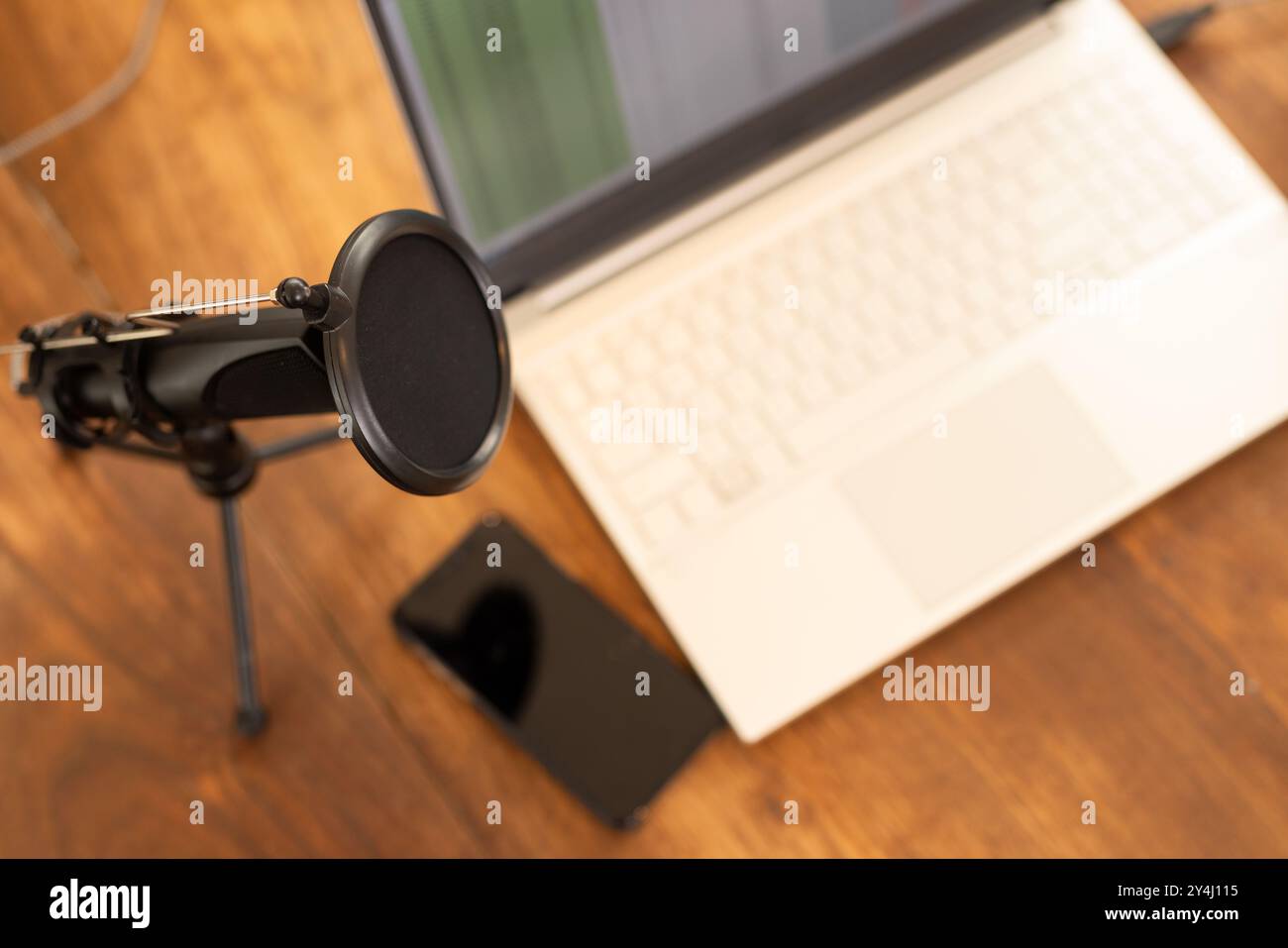 Configurazione podcasting con microfono, computer portatile e smartphone su scrivania in legno, spazio per le copie Foto Stock