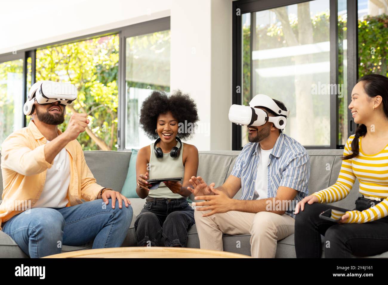 Utilizzando occhiali per realtà virtuale, giovani e diversi amici si divertono a giocare in realtà virtuale insieme Foto Stock