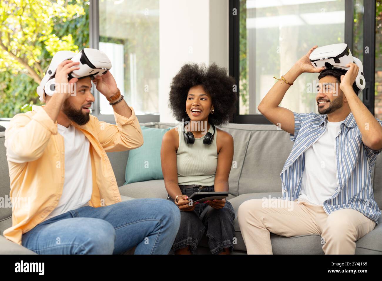 Utilizzando i visori per la realtà virtuale, i giovani e diversi amici si divertono con la realtà virtuale insieme Foto Stock