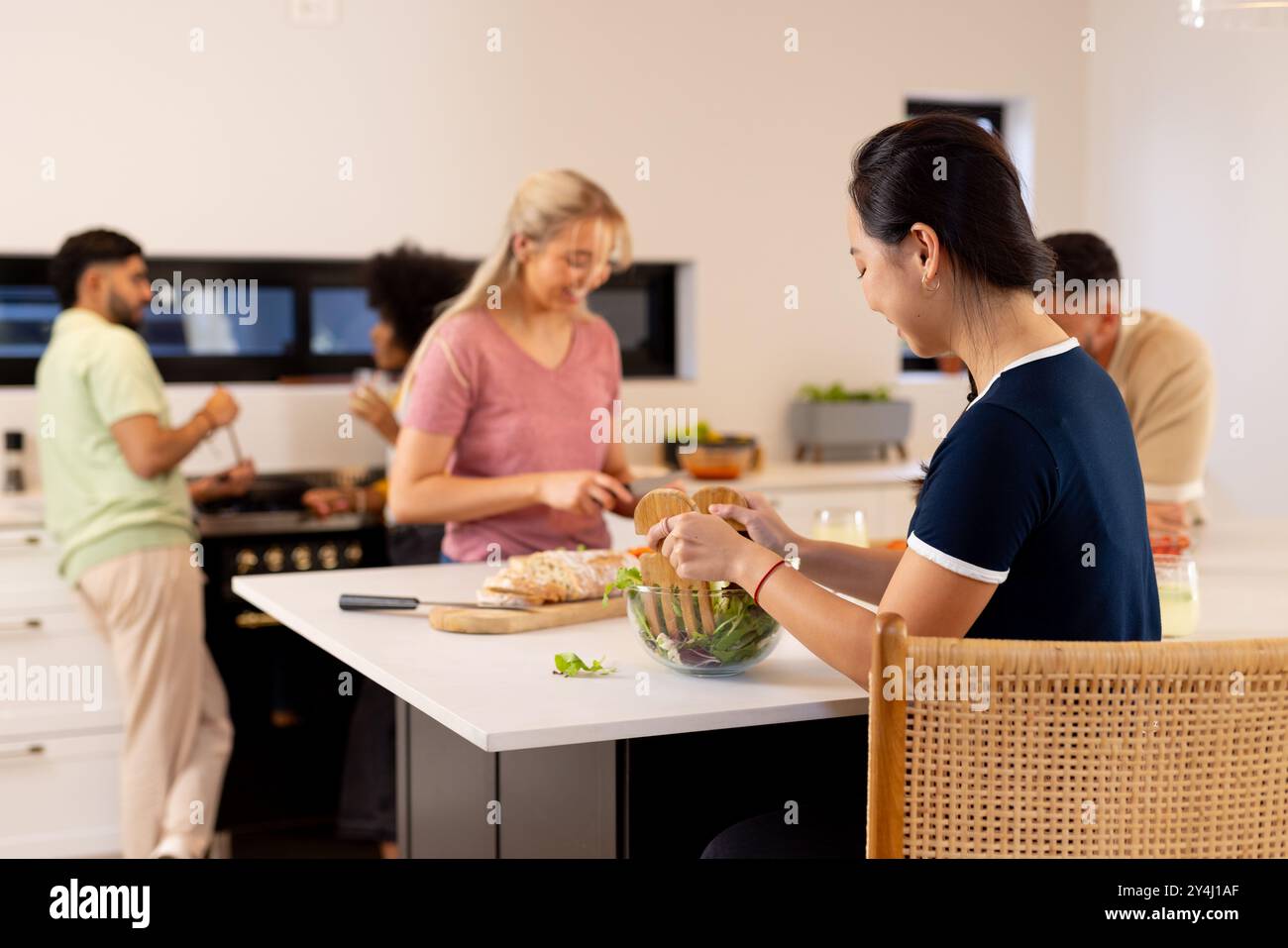 Preparare il cibo insieme, un gruppo di giovani e diversi amici che si divertono in cucina Foto Stock