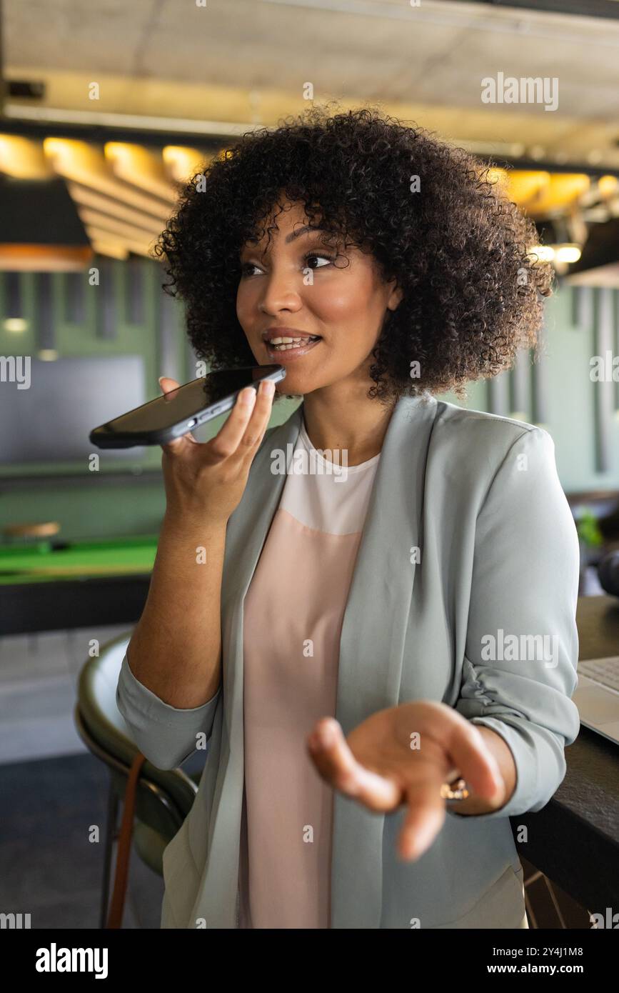 Parlare con lo smartphone, donna d'affari che utilizza l'assistente vocale in un ufficio moderno Foto Stock
