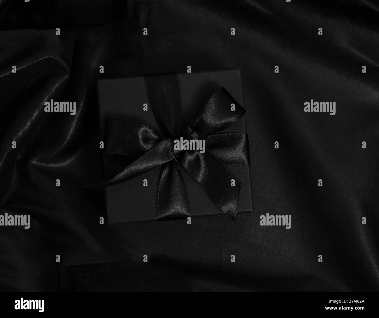 Promozione Black Friday. Confezione regalo con nastro e fiocco su raso nero, vista dall'alto, spazio copia Foto Stock