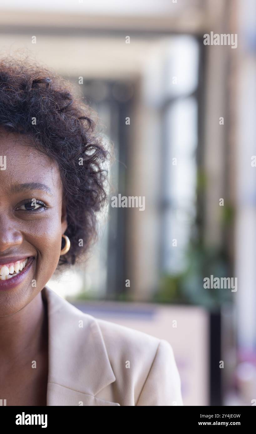 Donna sorridente in abiti da lavoro, che mostra fiducia e positività in ufficio Foto Stock